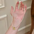 Elegant gold-plated pearl necklace featuring a rocking horse pendant shown on hand - Rocking Horse Coin Pearl Necklace / Gold-White