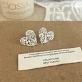 Detailansicht silberner herzförmiger Ohrstecker mit Spitzenmuster auf Kraftpapier - Silberne Herz Filigran Spitze Ohrstecker (A-1543)