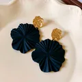 Close-up of elegant black textured flower earrings with gold studs shown on a plate - Mint Leaf Style / Gold and Black