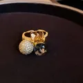 Detailed view of a gold-plated open ring with amber, black stones and a pavé zirconia ball - Real Gold Plated Style / Gold