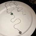 Detailed view of an elegant silver tassel necklace with a green zircon and metal ball - Tassel Style (HN9352) / Silver/Green