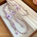 Detail showing purple pearl necklace with fabric flowers and lavender crystal teardrops. - Purple