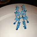 High detail view of elegant silver needle earrings with blue butterfly and flower crystals - Blue