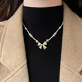 Elegant pearl necklace featuring a gold bow pendant encrusted with sparkling cubic zircon. - Artificial Pearl Bowknot Style / Necklace - Gold - White
