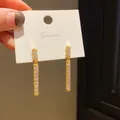 Close-up of gold bar earrings with sparkling white crystals on a display card. - Geometric Bar Dangle Style (9) / Gold
