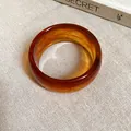 Primo piano di bracciale rigido in acrilico ambrato con elegante trama marmorizzata - Caffè Scuro