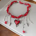 Detailed macro view of red gravel beads and silver heart cross pendant necklace - Red