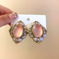 Dettaglio di orecchini vintage rosa con montatura dorata e strass scintillanti - Rosa Oro Caffè