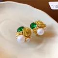 Vue détaillée des boucles d'oreilles vintage avec gemme verte, perle et rose dorée. - Or
