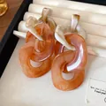 Macro view of amber and cream acrylic irregular chain link earrings in jewelry box - Amber
