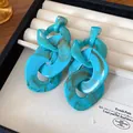 Detail shot of turquoise acrylic chain drop earrings with marble texture in a tray - Teal