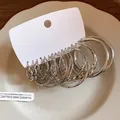 Detailed view of multiple silver geometric twisted hoop earrings arranged on white display card - Geometric Hoop Style (HE29433) / Silver