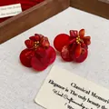 Close-up of vintage red shell stud earrings with ethnic stone details on linen background - Red