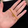 Dettaglio di un bracciale placcato in oro con fiori di zircone e ciondoli con pietre rosa - Bracciale Oro Sabbia