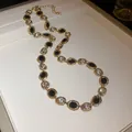 Close-up of elegant gold-toned necklace with black and clear oval rhinestones on white surface - Necklace / Gold Base Black and White Stones