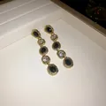 Detailed view of elegant gold drop earrings featuring black and clear irregular oval stones - Drop Earrings / Gold Base Black and White Stones