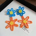 Handmade crochet flower earrings in vibrant blue and orange with yellow bead centers - Style 28