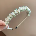 Nahaufnahme von cremefarbenen Satinrosen und grünen Blättern auf einem eleganten Haarreif - Grünes Blatt Stoffblumen Stil / Weiß