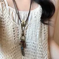 Primo piano di una collana bohémien con ciondoli vintage a stella e piuma su una modella - Piccola Piuma (1#)