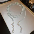 Macro view of long multi-layer pearl necklace with elegant teardrop pendants. - White