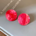 Close-up of pink marbled acrylic round stud earrings with gold glitter flakes. - Pink