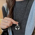 Silver headphone pendant necklace with black cord worn by model as a stylish sweater chain. - Silver