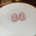 Macro detail of elegant pink cameo stud earrings with white pearl border on ceramic plate. - Cameo Portrait (20#) / Pink / Silver Needle