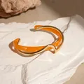 Bracciale rigido aperto in metallo dorato e acrilico arancio dal design ondulato - Oro e Caffè