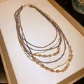 Close-up of vintage multi-layered necklace with amber glass beads and gold chains. - Layered Necklace / Brown