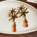 Macro detail of vintage gold flower earrings with amber resin water drop tassels - Resin Flower Water Drop Tassel Earrings (WE2476) / Gold Brown