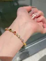 Dettaglio di un bracciale dorato con zirconi multicolore indossato al polso - Oro