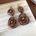 Primer plano de pendientes vintage envueltos en alambre con cuentas de cristal. - Estilo Redondo Tejido / Marrón dorado