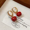 Close-up of gold-plated hoop earrings with sparkling zircons and glossy red apple charms. - Red Apple Ear Buckle