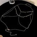 Close-up of golden multi-layer body chain with hanging sequin discs on black surface - Sequin Style / Gold