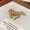 Macro view of a golden running horse brooch with sparkling rhinestone saddle details - Gold