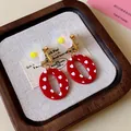 Primer plano detallado de pendientes de resina roja con corazones blancos y flor - Pendientes de clip / Blanco-Rojo
