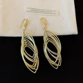 Detailed view of gold-colored layered oval dangle earrings with pleated texture. - Hook Style / Gold