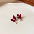 Close-up detail of elegant red flocked butterfly stud earrings with pearl and crystal - Butterfly Pearl Style / Red