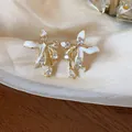 Detail view of 18k gold plated flower stud earrings with white enamel and clear zircon. - Silver Earring Post Style / Gold-White