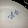 Primo piano di orecchini a lobo a farfalla in argento e zirconi su un piatto beige - Design a Farfalla / Argento