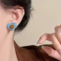 Detailed view of heart-shaped earrings with blue denim fabric and brown resin heart charm - Denim Blue