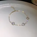 Gros plan d'un bracelet en zircon doré avec motifs fleurs ajourées sur plat blanc - Or