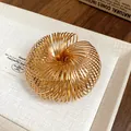 Nahaufnahme eines goldenen Spiral-Metallarmreifs mit hochglänzender Spiegeloberfläche - Spiral Offener Armreif / Gold