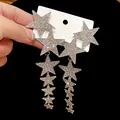 Detailed view of long silver needle tassel earrings featuring sparkling rhinestone stars - Star Tassel Long Pendant / Silver