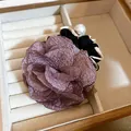 Close-up detail of a dusty purple fabric flower hair scrunchie with large pearl bead - Purple