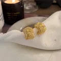Dettaglio di orecchini a cerchio in metallo dorato a forma di C multistrato su tovagliolo. - Stile Cerchio a C Avvolto Texturizzato (20#) / Oro