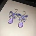 Nahaufnahme von lila Zirkon-Schmetterlingsohrringen mit eleganten Kristallanhängern - Schleife Ohrhaken (WE3744) / Lila