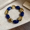 Dettaglio di un bracciale elastico vintage con perline dorate e blu glitterate. - Bracciale / Blu