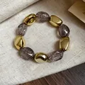 Dettaglio di un bracciale elastico vintage in acrilico con perle dorate e glitterate - Bracciale / Grigio