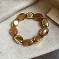 Vista dettagliata di un braccialetto elastico vintage in perline acriliche ambra e oro. - Bracciale / Caffè Chiaro